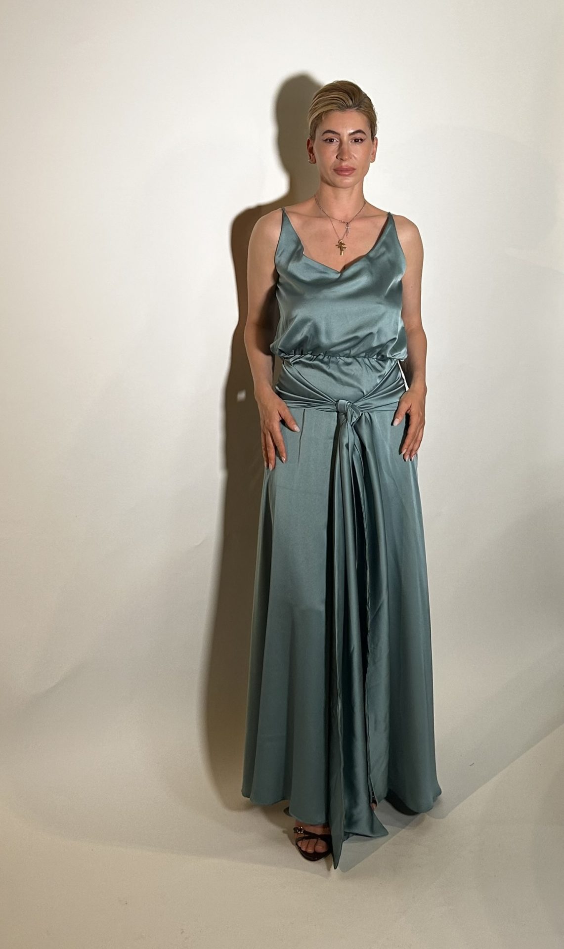 IMG_1644 (3) Vestito raso verde e un vestito da damigella lungo fino ai piedi realizzato in raso presenta uno scollo ampio a V davanti e uno scollo tondo dietro .Una fascia da dietro che si ports davanti con uno nodo centrale e una lunghezza che aggiunge liberta di movimento e un tocco moderno. Misure taglia M Spalle 36 cm Seno 92 cm Giro vita 48cm Fianchi 100cm Lunghezza vestito 150 cm