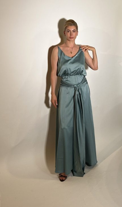 Vestito raso verde e un vestito da damigella lungo fino ai piedi realizzato in raso presenta uno scollo ampio a V davanti e uno scollo tondo dietro .Una fascia da dietro che si ports davanti con uno nodo centrale e una lunghezza che aggiunge liberta di movimento e un tocco moderno. Misure taglia M Spalle 36 cm Seno 92 cm Giro vita 48cm Fianchi 100cm Lunghezza vestito 150 cm