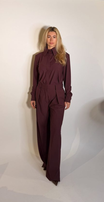 Pantalone dal design sartoriale e contemporaneo caratterizzato da una silhouette ampia e fluida e da una linea elegante e strutturata. Il modello presenta vita regolare, pinces fontali e una gamba larga dritta che slancia la figura mantenendo un estetica essenziale e sofisticata.